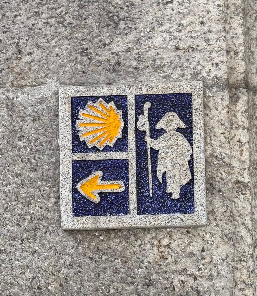 Azulejo com concha amarela, flecha e peregrino em fundo azul